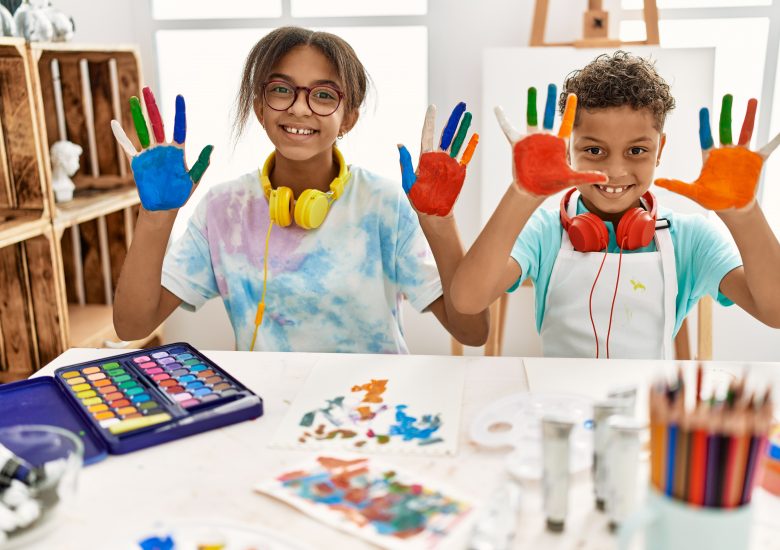 Two children with paint on their hands and a table