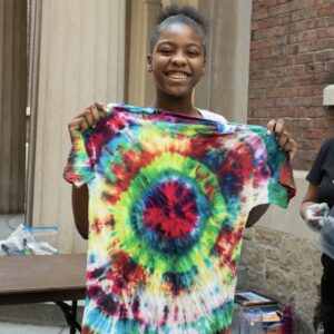 A girl holding up a tie dye shirt.