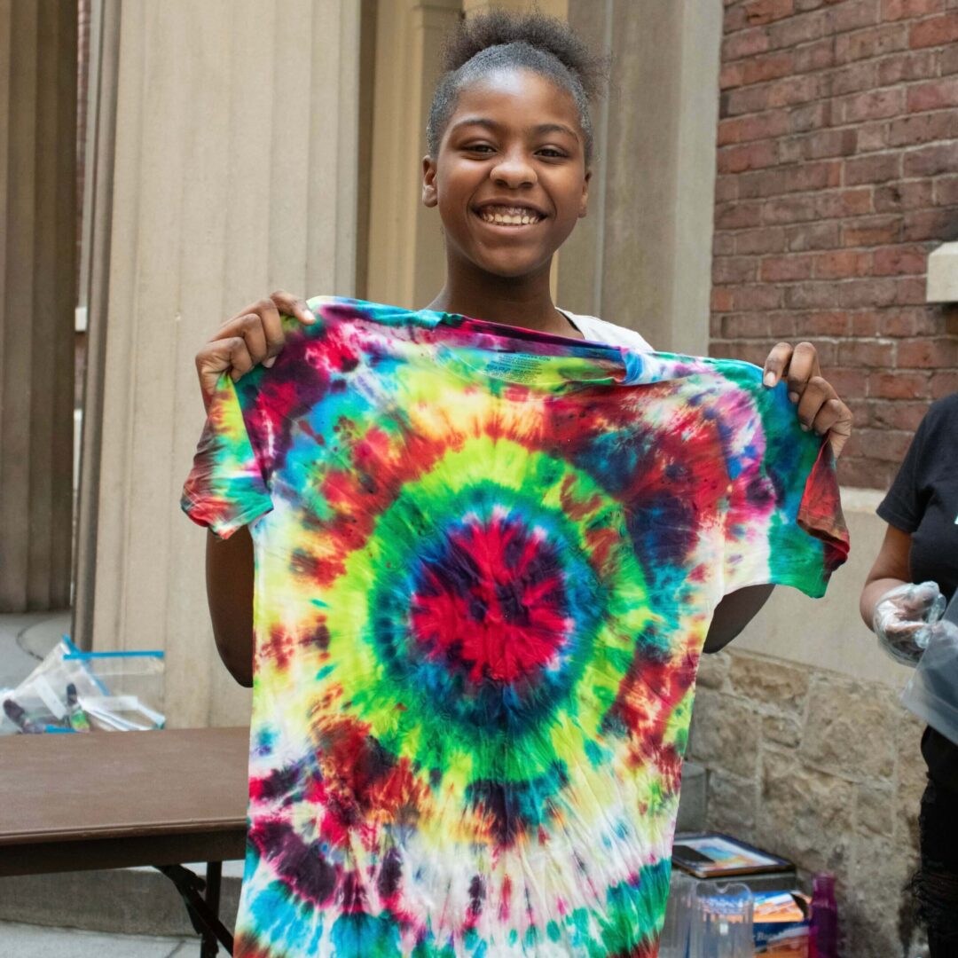 A girl holding up a tie dye shirt