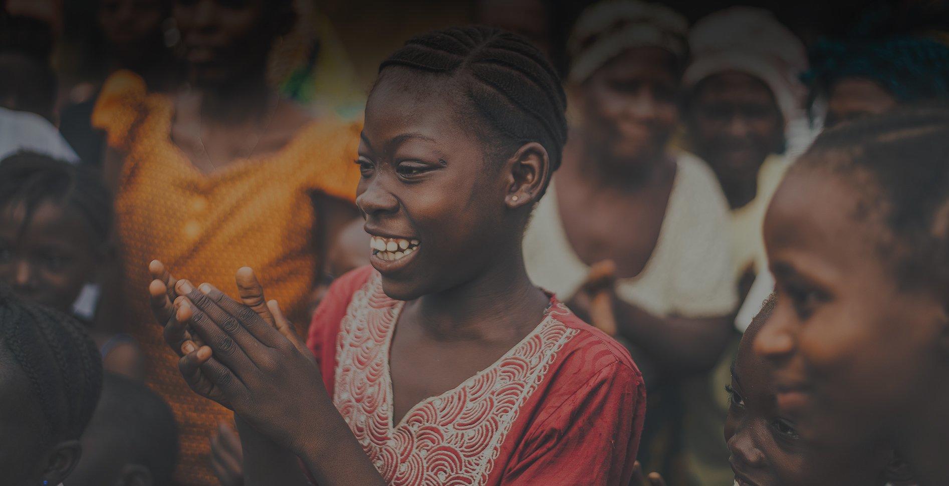A young girl smiling and holding her hands up.